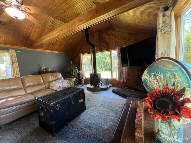 living area featuring a ceiling fan, wood ceiling, beamed ceiling, a wood stove, and high vaulted ceiling