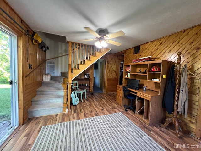 home office featuring ceiling fan, wood finished floors, and wooden walls