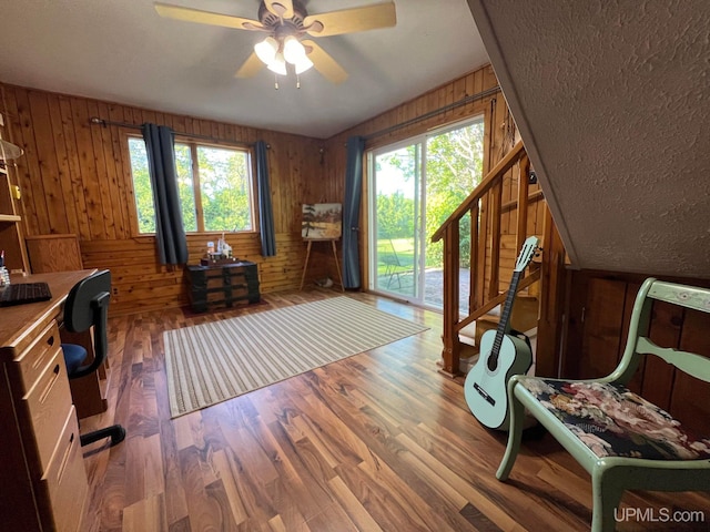 office space featuring wood walls, ceiling fan, and dark wood finished floors