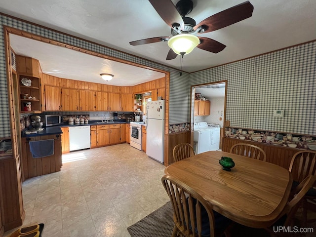 kitchen featuring white appliances, wallpapered walls, dark countertops, brown cabinets, and separate washer and dryer