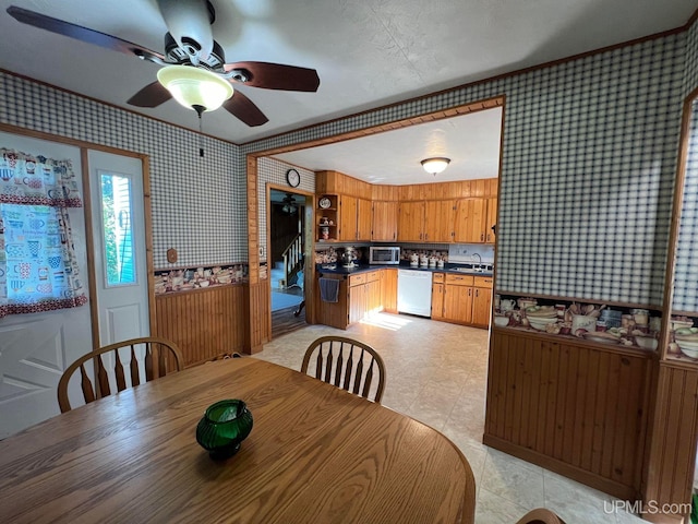 dining space with a ceiling fan and wallpapered walls