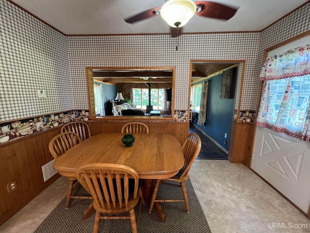 dining room with light tile patterned flooring, visible vents, a ceiling fan, ornamental molding, and wallpapered walls