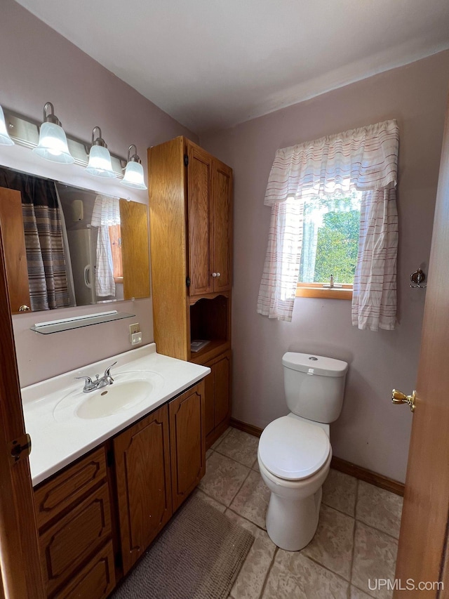 bathroom featuring toilet, tile patterned flooring, baseboards, and vanity