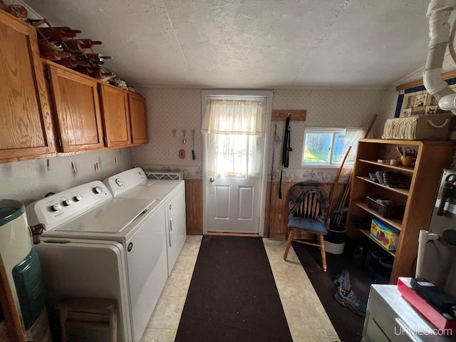 laundry area featuring a textured ceiling, separate washer and dryer, cabinet space, and wallpapered walls