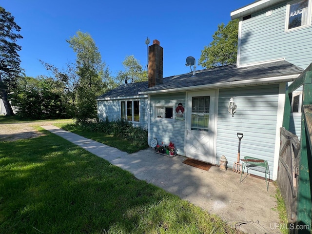 rear view of property with a patio area, a lawn, and a chimney