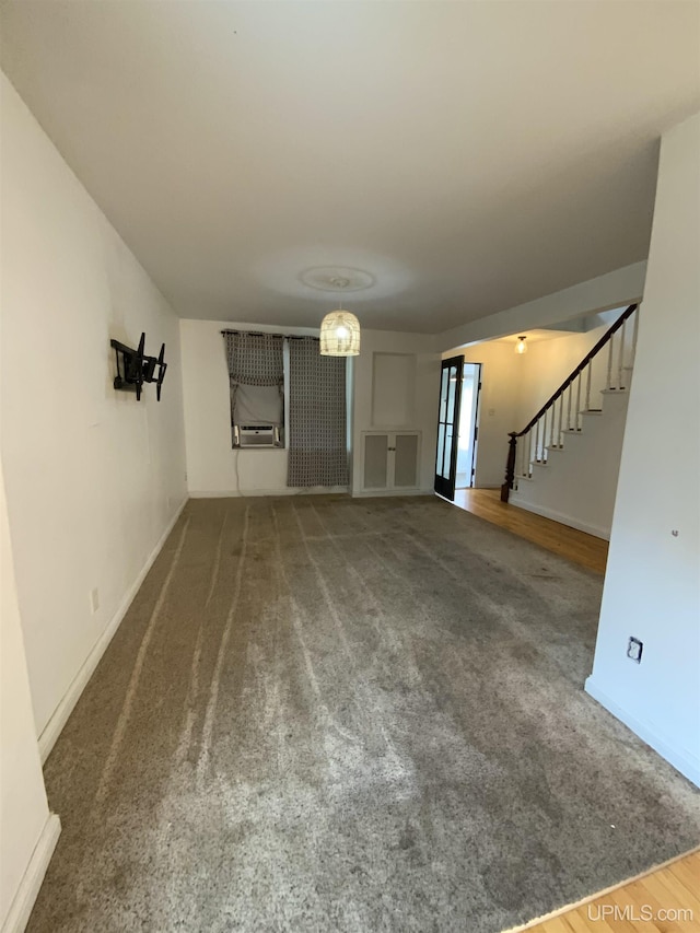 unfurnished living room with carpet, stairs, baseboards, and cooling unit