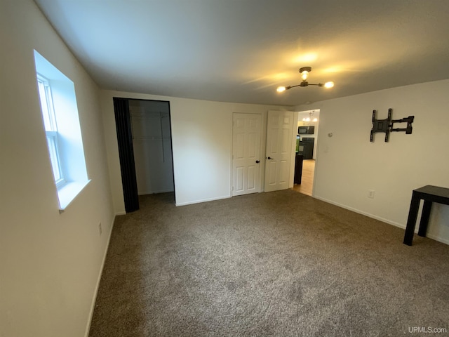 unfurnished bedroom with dark carpet, two closets, and baseboards