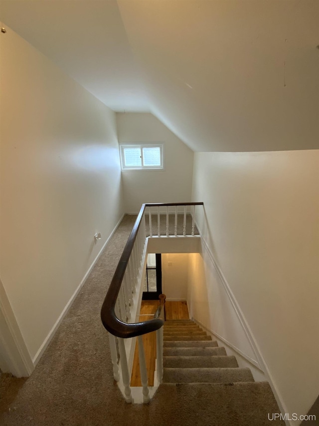 staircase featuring vaulted ceiling, carpet flooring, and baseboards