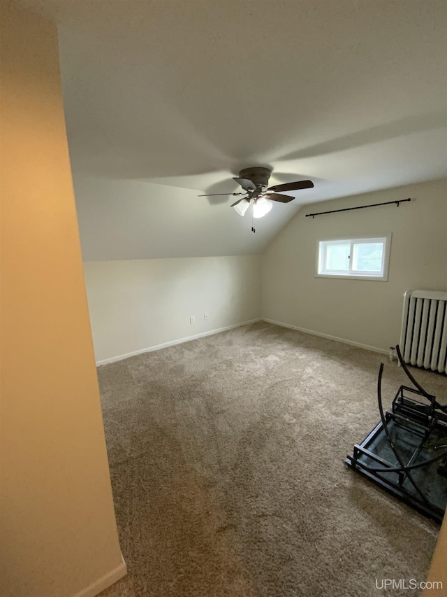 empty room featuring lofted ceiling, radiator heating unit, carpet flooring, and baseboards