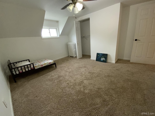 unfurnished bedroom with a closet, radiator, carpet flooring, vaulted ceiling, and baseboards