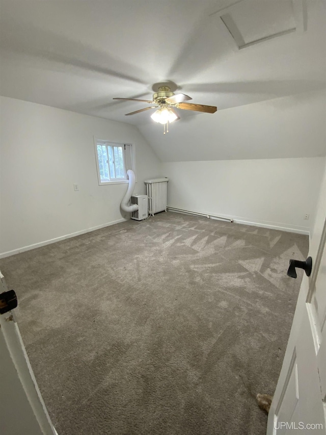 additional living space with carpet floors, baseboards, vaulted ceiling, radiator heating unit, and attic access