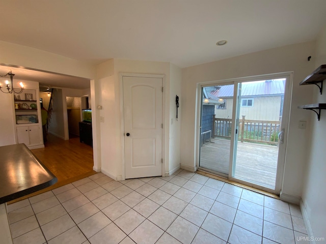 spare room featuring a notable chandelier and light tile floors