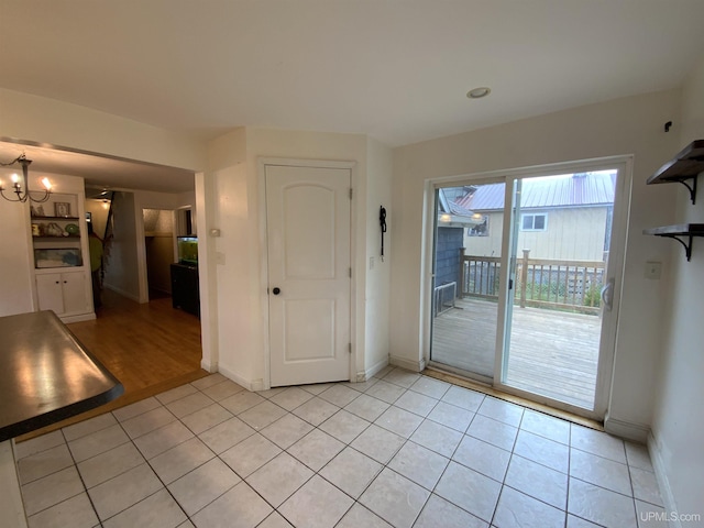 interior space with a notable chandelier, baseboards, and light tile patterned floors