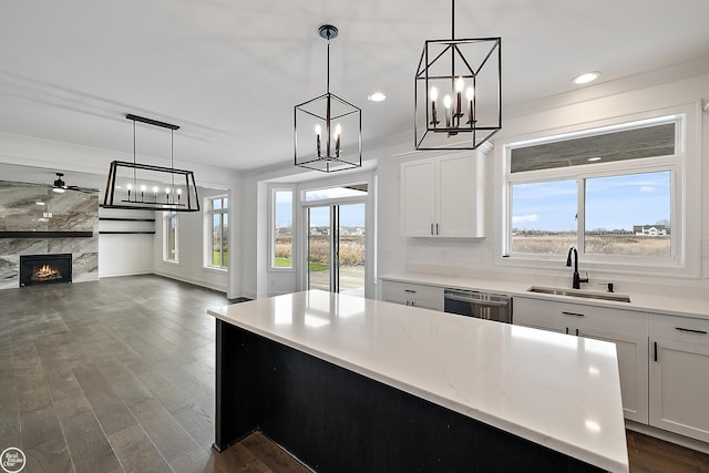 kitchen featuring white cabinetry, a fireplace, hanging light fixtures, and stainless steel dishwasher