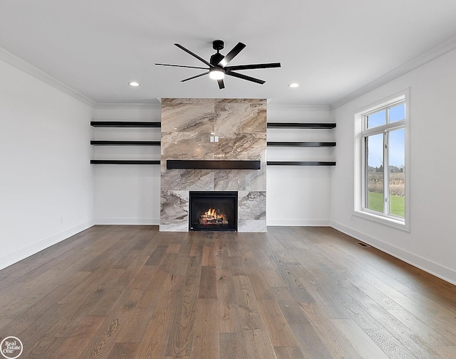 unfurnished living room with a tiled fireplace, crown molding, hardwood / wood-style floors, and ceiling fan