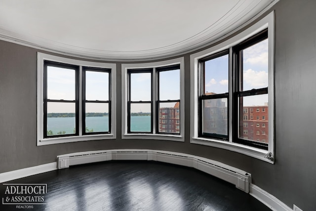 empty room featuring a baseboard heating unit, a water view, ornamental molding, and hardwood / wood-style flooring