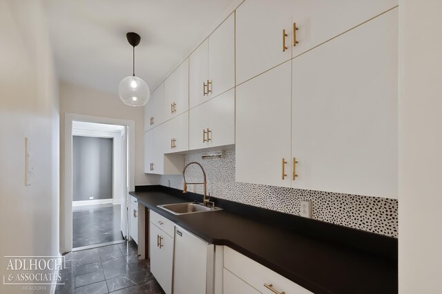 kitchen featuring white cabinets, decorative light fixtures, backsplash, sink, and dark tile flooring