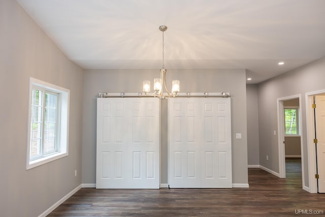 unfurnished dining area featuring a chandelier and dark wood-type flooring