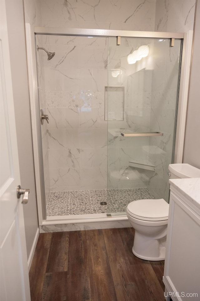 bathroom featuring a shower with shower door, hardwood / wood-style flooring, vanity, and toilet