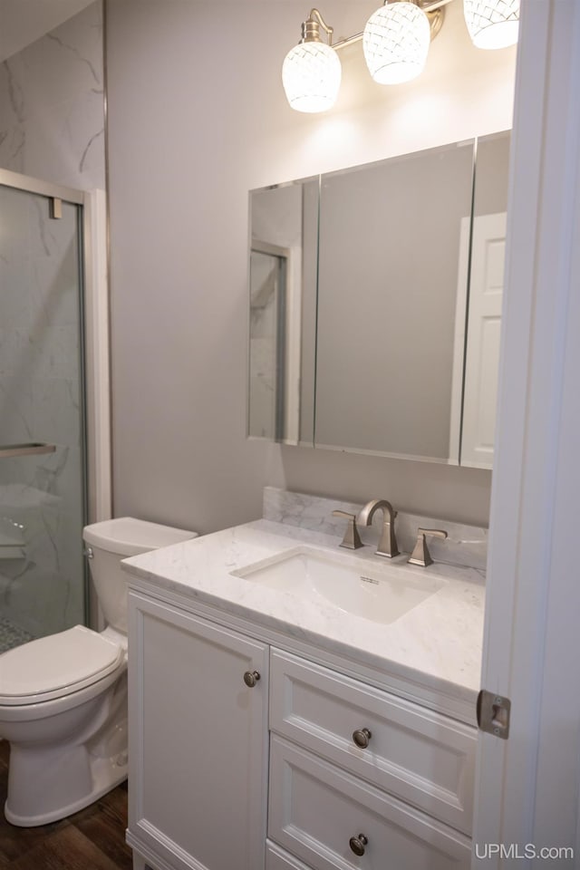 bathroom featuring a shower with door, hardwood / wood-style flooring, vanity, and toilet