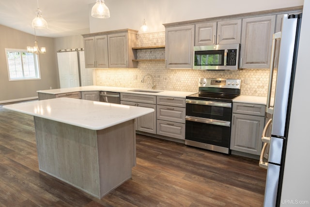 kitchen featuring dark hardwood / wood-style floors, backsplash, hanging light fixtures, sink, and appliances with stainless steel finishes