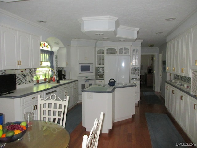 kitchen featuring white appliances, tasteful backsplash, dark hardwood / wood-style flooring, a center island, and white cabinets