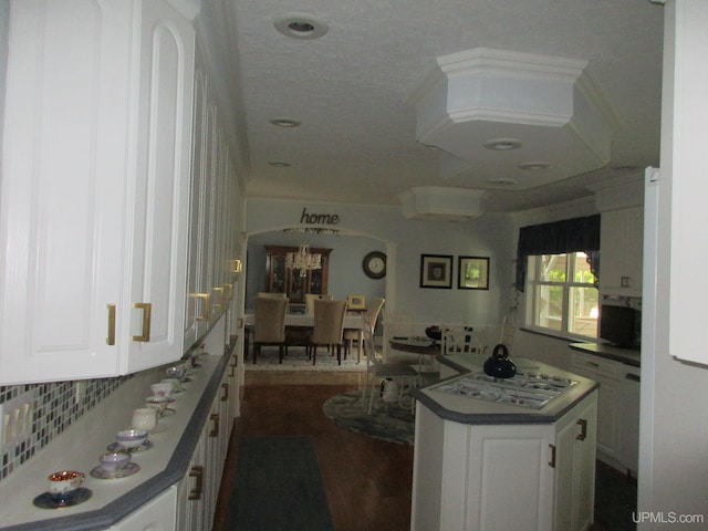 kitchen with a kitchen island, white gas stovetop, dark hardwood / wood-style floors, and white cabinetry