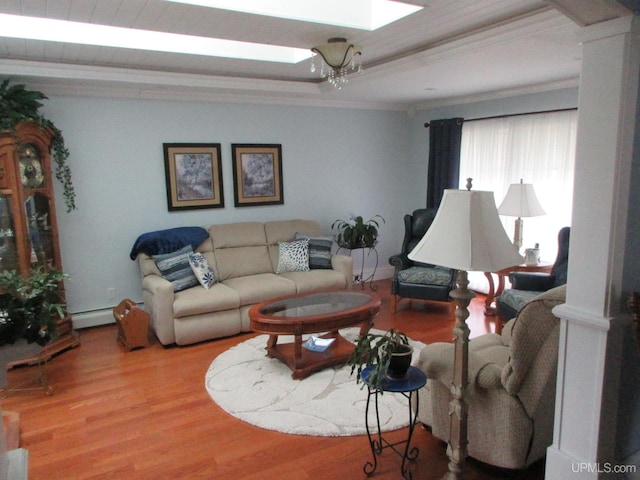 living room featuring a skylight, crown molding, a baseboard heating unit, hardwood / wood-style floors, and ornate columns