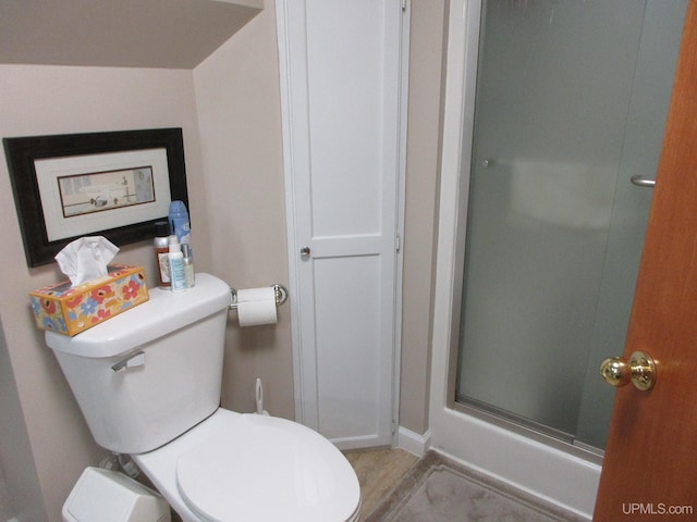 bathroom featuring a shower with door, toilet, and wood-type flooring