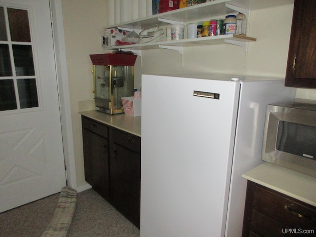 kitchen featuring white refrigerator, dark brown cabinets, and carpet