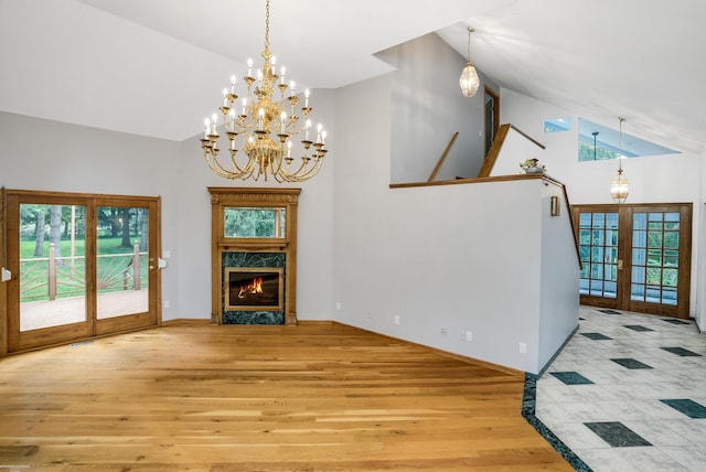 unfurnished living room featuring light hardwood / wood-style floors, a fireplace, high vaulted ceiling, and french doors