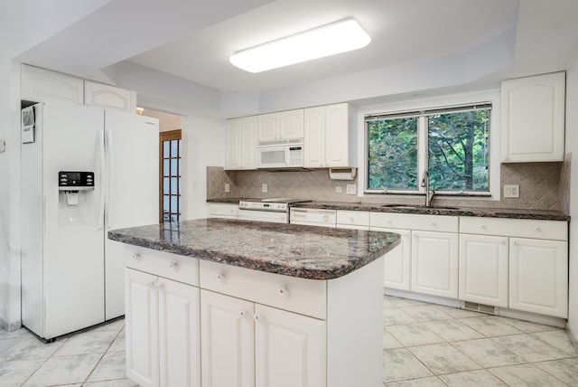 kitchen with white cabinetry, sink, a center island, backsplash, and white appliances