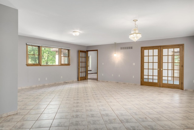 empty room with an inviting chandelier, light tile patterned floors, and french doors