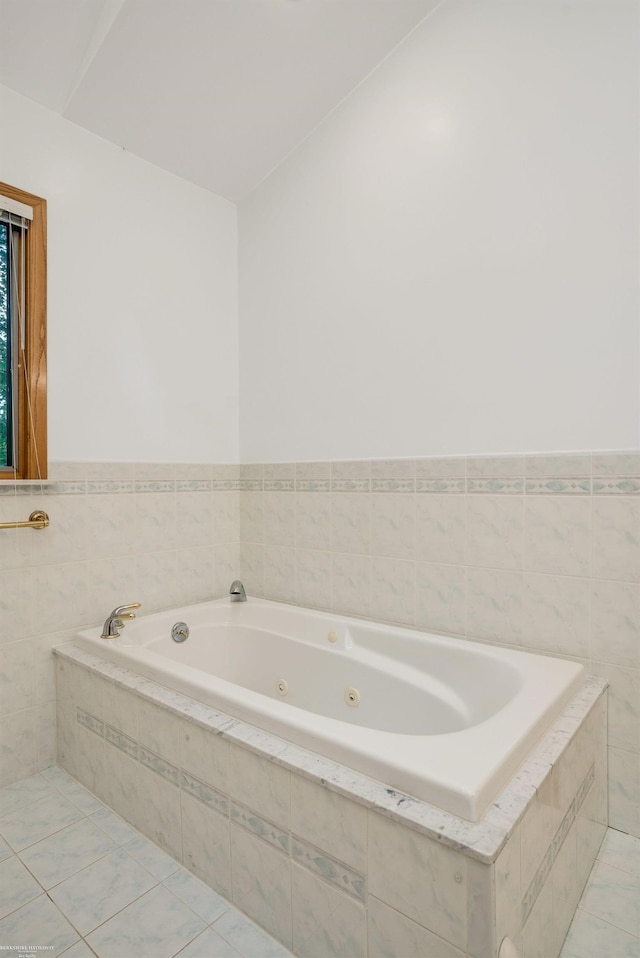 bathroom with tile patterned flooring and tiled tub