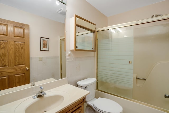 full bathroom with vanity, enclosed tub / shower combo, tile walls, and toilet