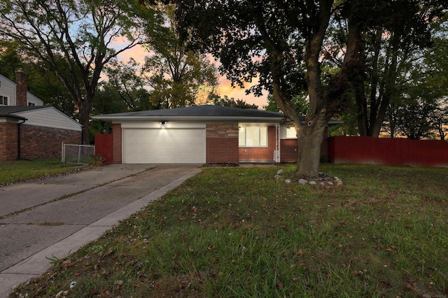 ranch-style house featuring a garage and a lawn