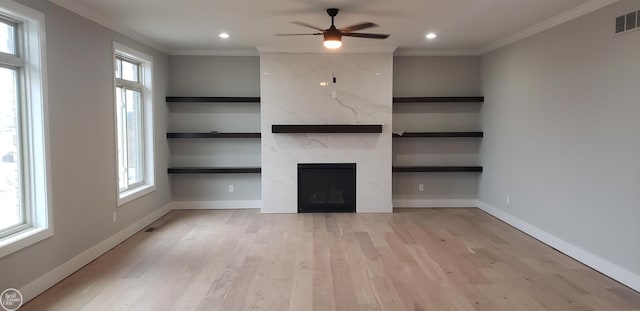 unfurnished living room with plenty of natural light, a premium fireplace, and built in shelves