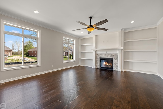 unfurnished living room with ceiling fan, crown molding, built in features, a fireplace, and dark hardwood / wood-style floors