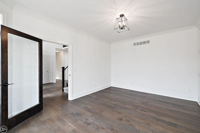 spare room with french doors, a chandelier, dark hardwood / wood-style floors, and ornamental molding