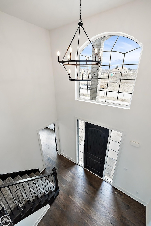 entryway with dark wood-type flooring and an inviting chandelier