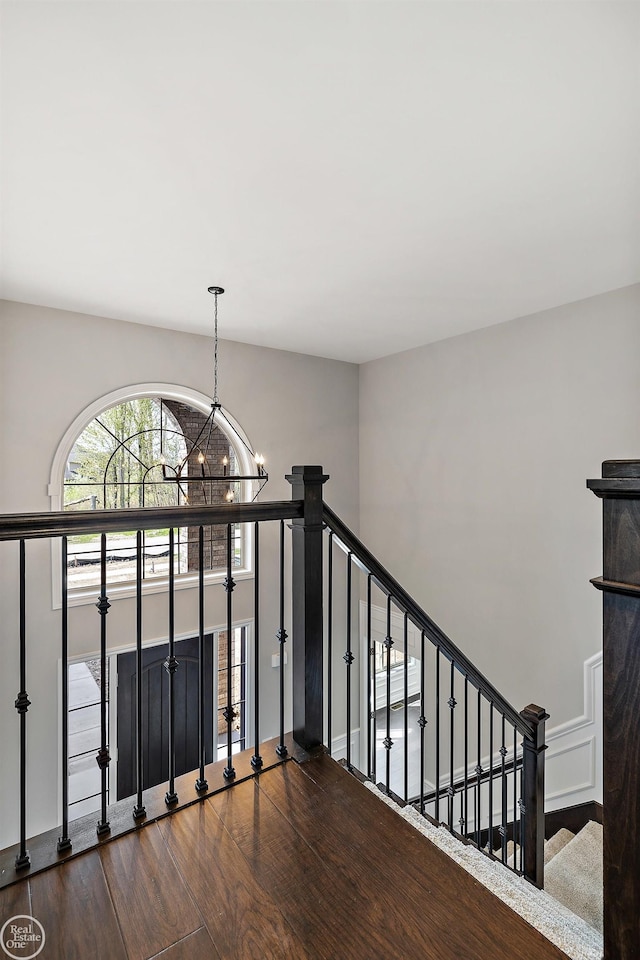 stairs featuring hardwood / wood-style floors and a chandelier