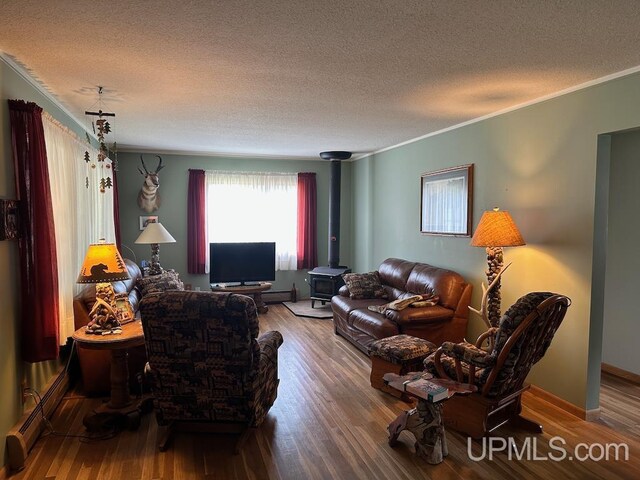 living room with wood-type flooring, baseboard heating, a wood stove, and a textured ceiling