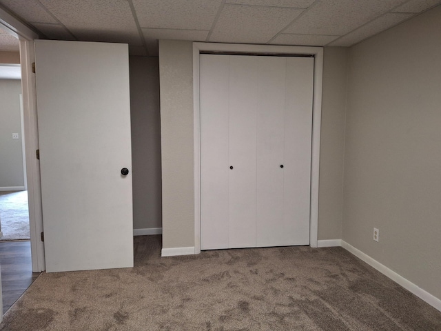 unfurnished bedroom featuring a closet, carpet, and a drop ceiling