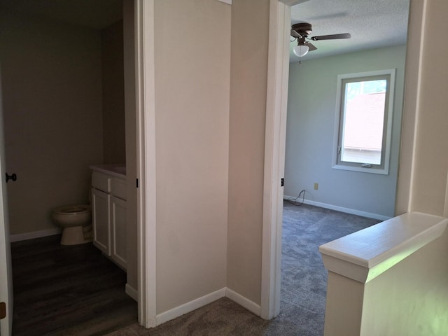 hallway featuring a textured ceiling and dark colored carpet