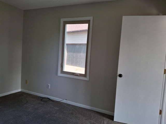 spare room featuring dark colored carpet