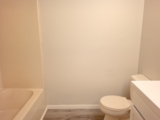 bathroom featuring vanity, wood-type flooring, a tub, and toilet