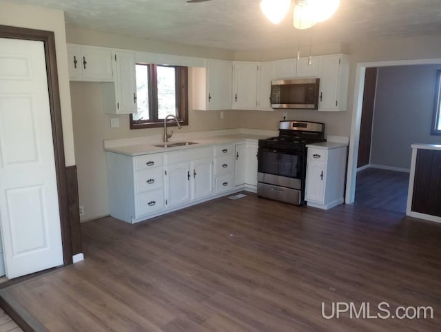 kitchen with ceiling fan, sink, dark hardwood / wood-style floors, white cabinets, and appliances with stainless steel finishes