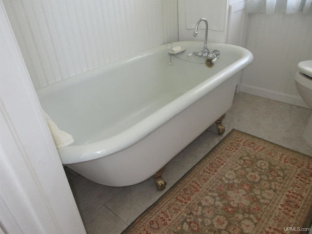 bathroom with tile patterned flooring, toilet, and a tub