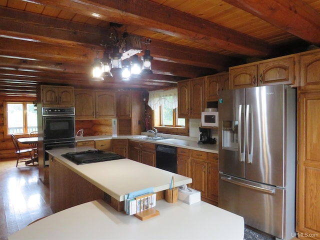 kitchen featuring beamed ceiling, black appliances, and plenty of natural light