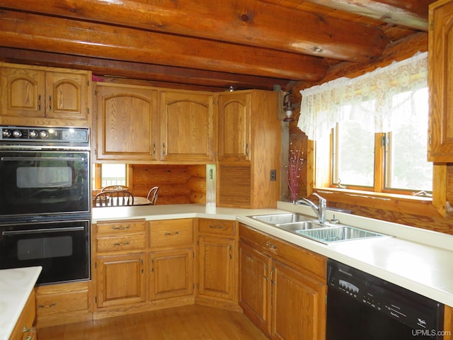 kitchen with beamed ceiling, black appliances, light hardwood / wood-style flooring, and sink